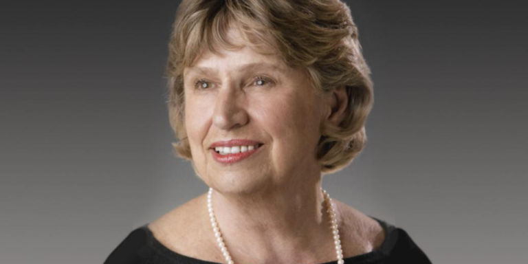 A portrait of a woman in pearls and a black top