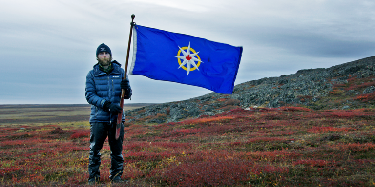 A man holds a flag in a arctic field