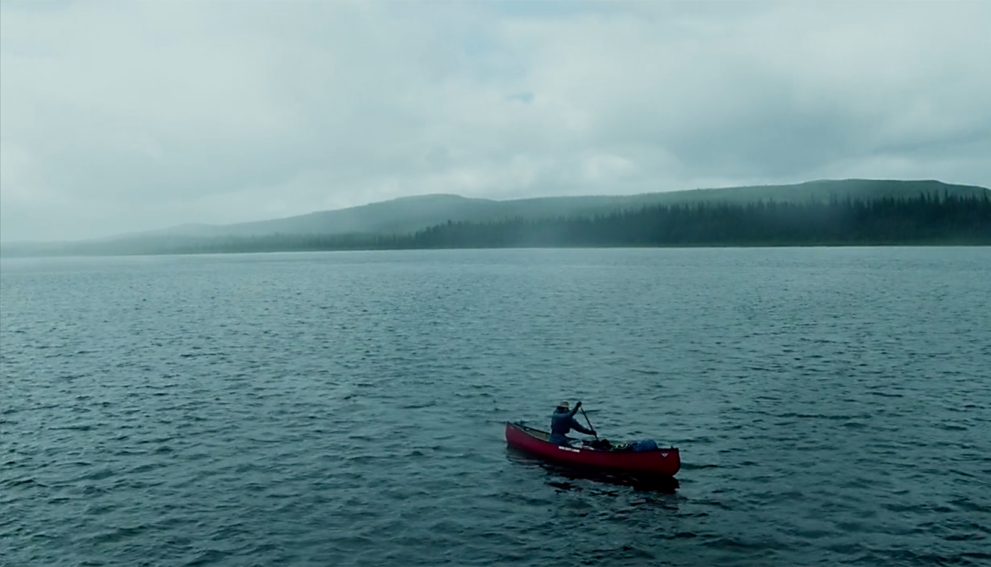A man paddles a canoe on a lake